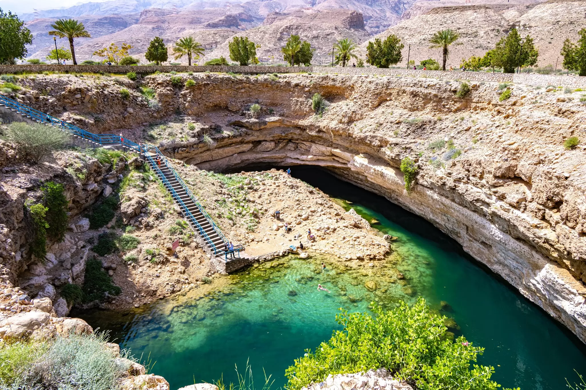 Steps lead down to a sinkhole with turquoise waters; Bimmah Sinkhole, Oman.