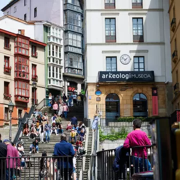 View of the Arkeologi Museoa and the stairs of the Calzadas de Mallona full of people in Bilbao, Spain.