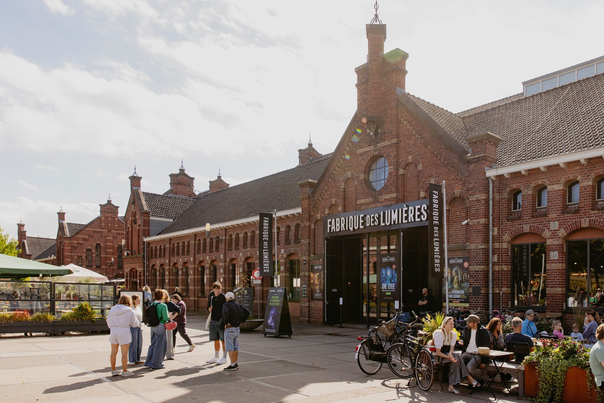 People sit outside the entrance to the Fabrique des Lumières gallery at Cultural Park Westergas in Amsterdam.