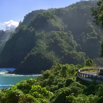 Curvy coastal road with views of cliffs, beaches, waterfalls.