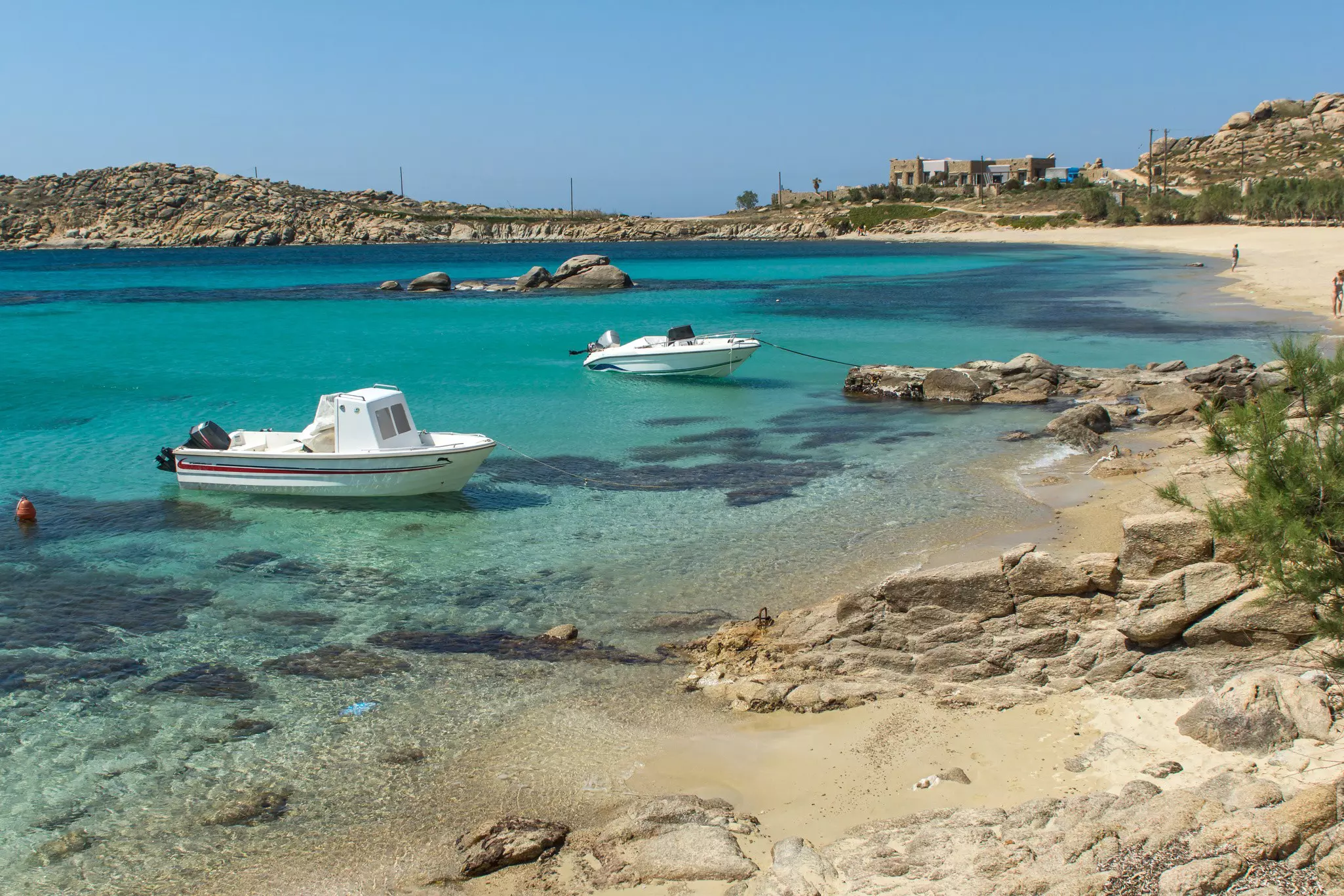 Two small boats moored in the shallows of a sandy beach.