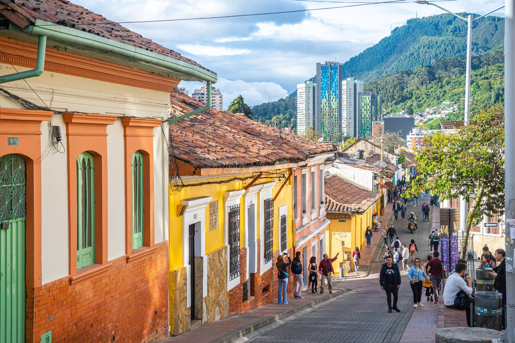Colorfully painted low-rise buildings, with skyscrapers against a hillside in the background.