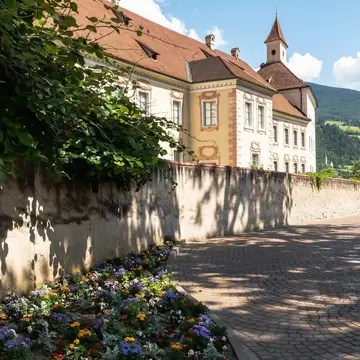 Baroque facade and tower of the Hofburg behind a flower-lined wall, home of the Diözesanmuseum in Bressanone