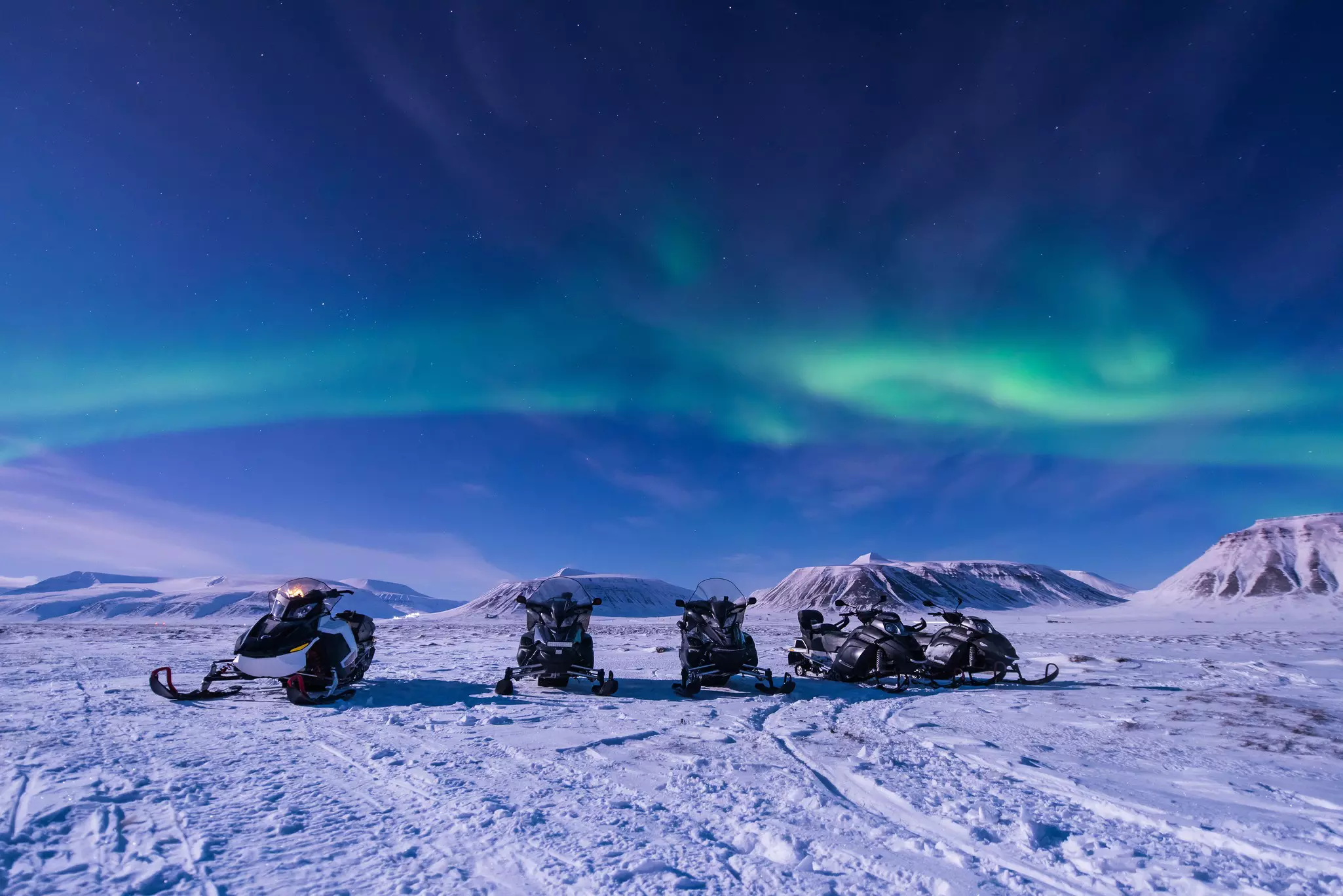 A group of snowmobiles under the Northern Lights.