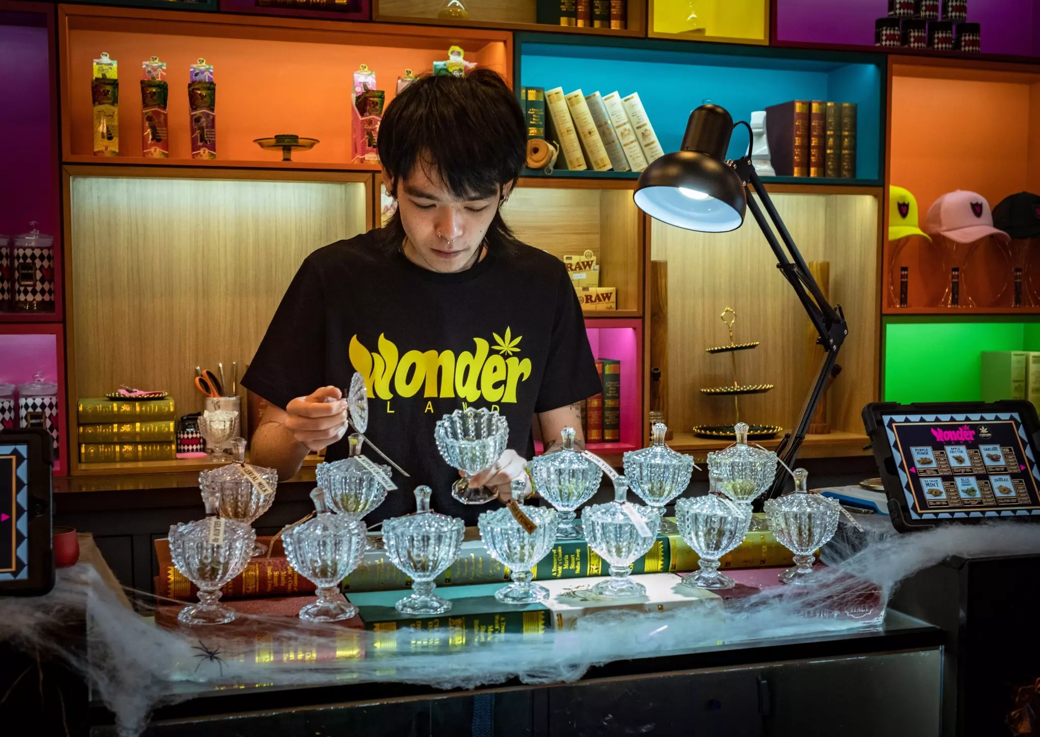A shop worker selects varieties of marijuana displayed in glass goblets at a dispensary.