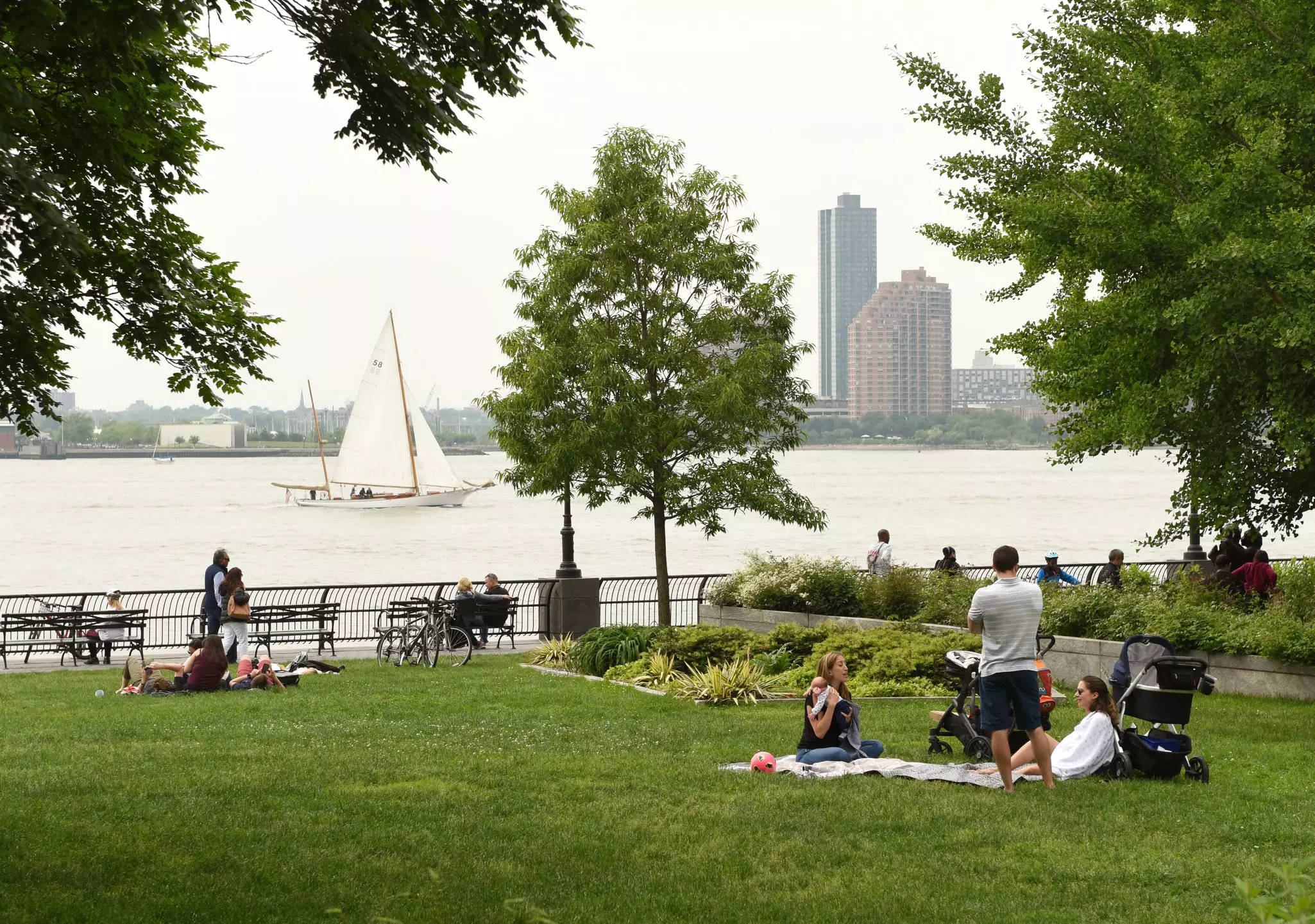 People sit in small groups on grass beside a river