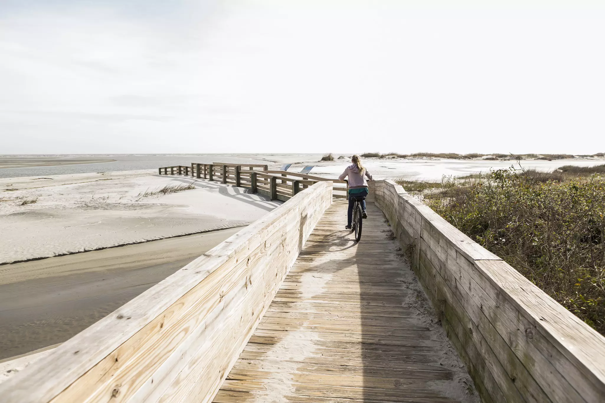 Girl walking on boardwalk to the beach on Jekyll Island, Georgia