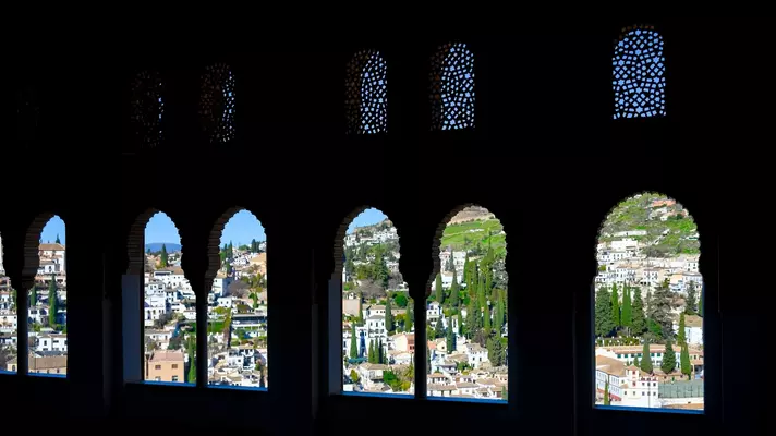 View of Granada through the distinct horseshoe-shaped arches of the Alhambra.