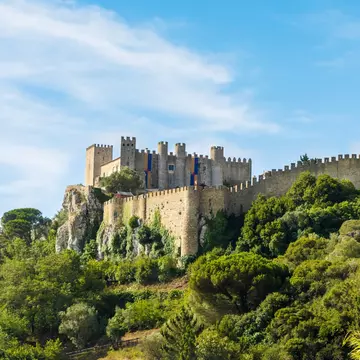 View of the Castelo de Óbidos on a hilltop covered in trees in Portugal.
