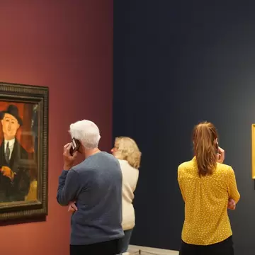 Visitors of the special exhibition on Amedeo Modigliani in Museum Barberini using their smartphones as audio guides in Potsdam, Germany.