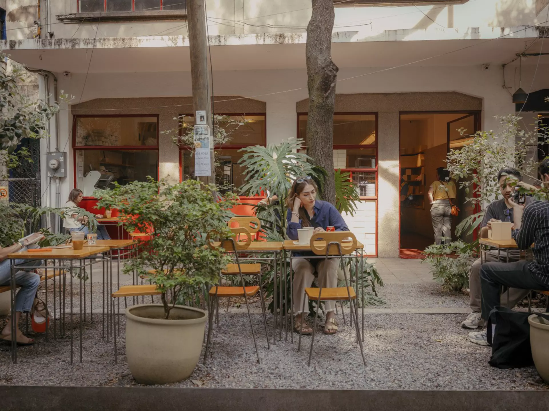 People sit at outdoor tables among plants in front of a bakery in Mexico City.