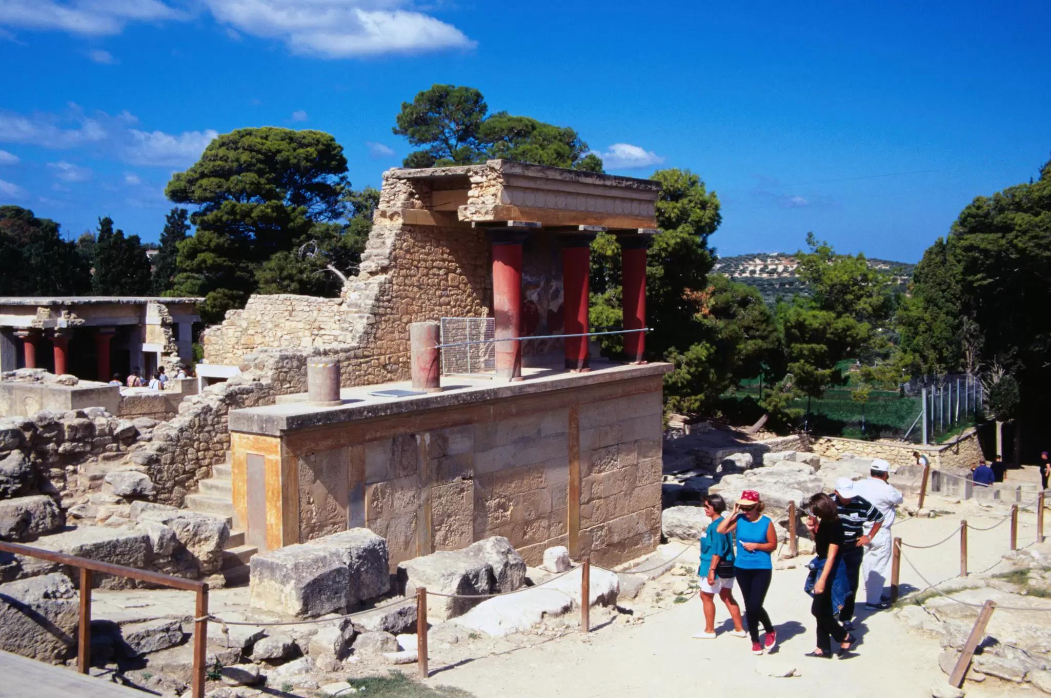A group of people walk past the ruins of the Palace of Knossos, in Crete, Greece.