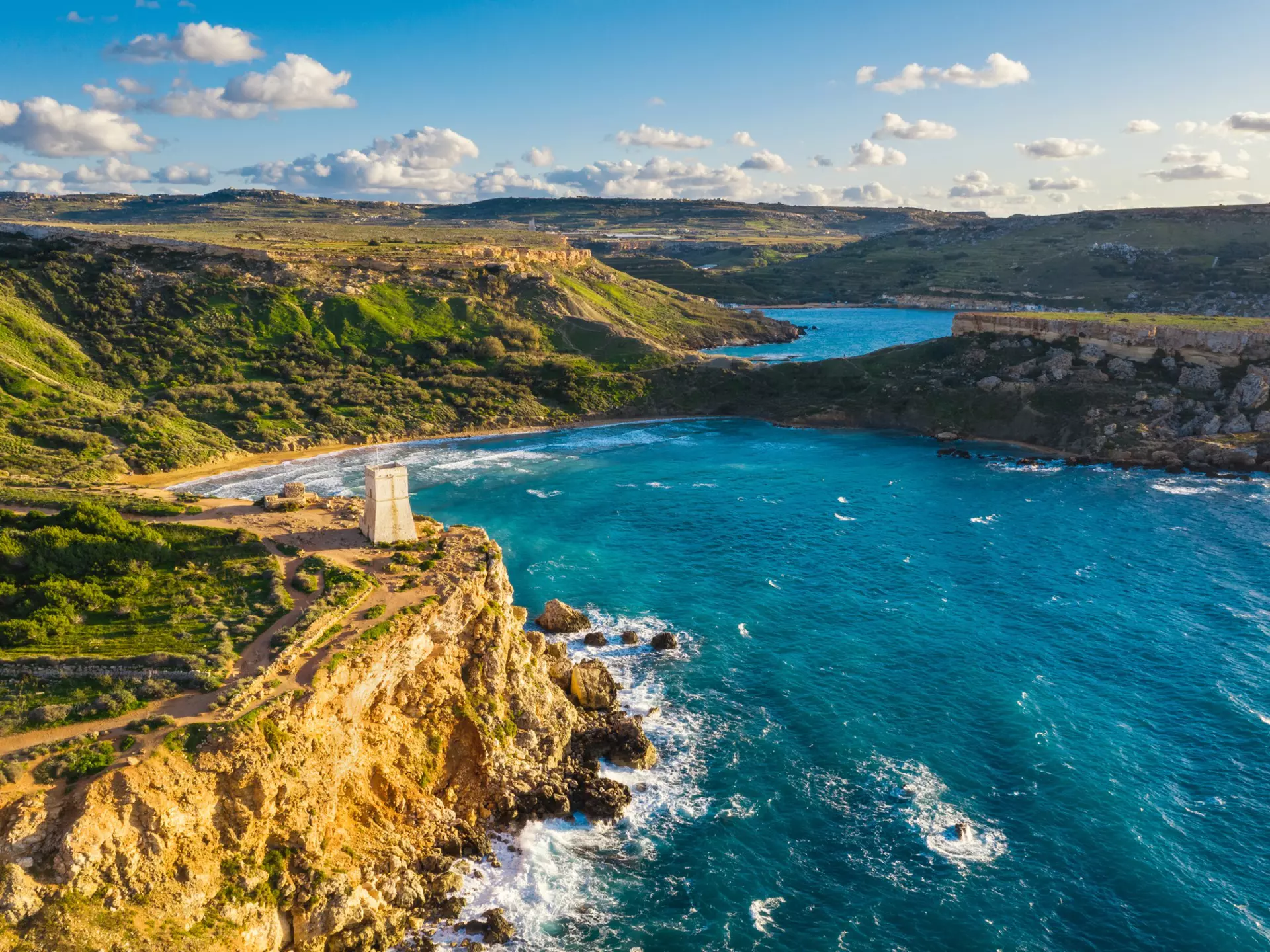 A rocky coastline with golden strand of beach tucked among cliffs.