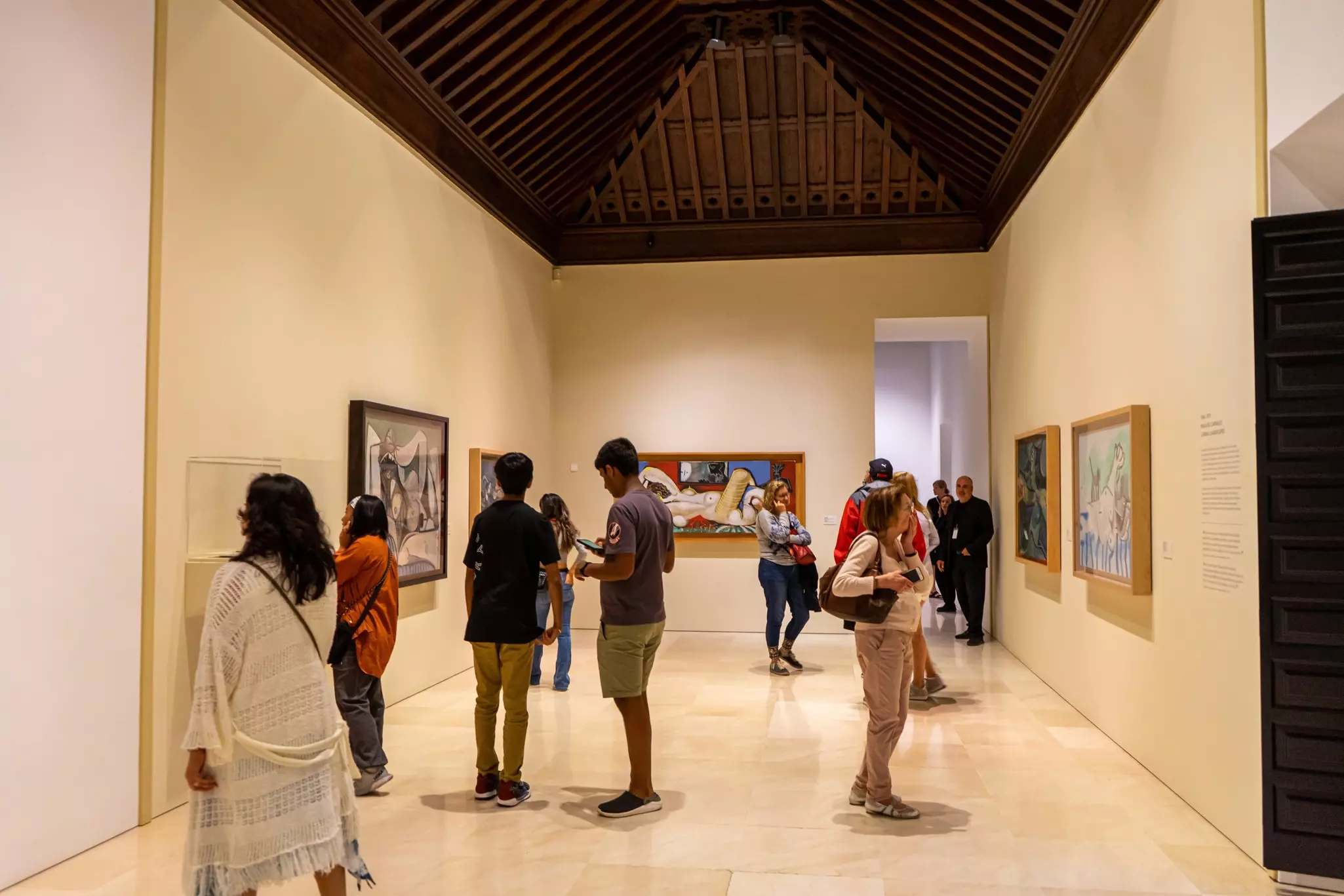 People look at artworks in a museum gallery.