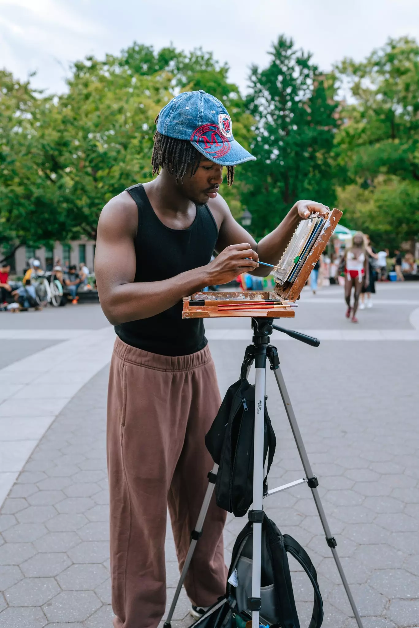 A young man paints a picture in Washington Square Park.