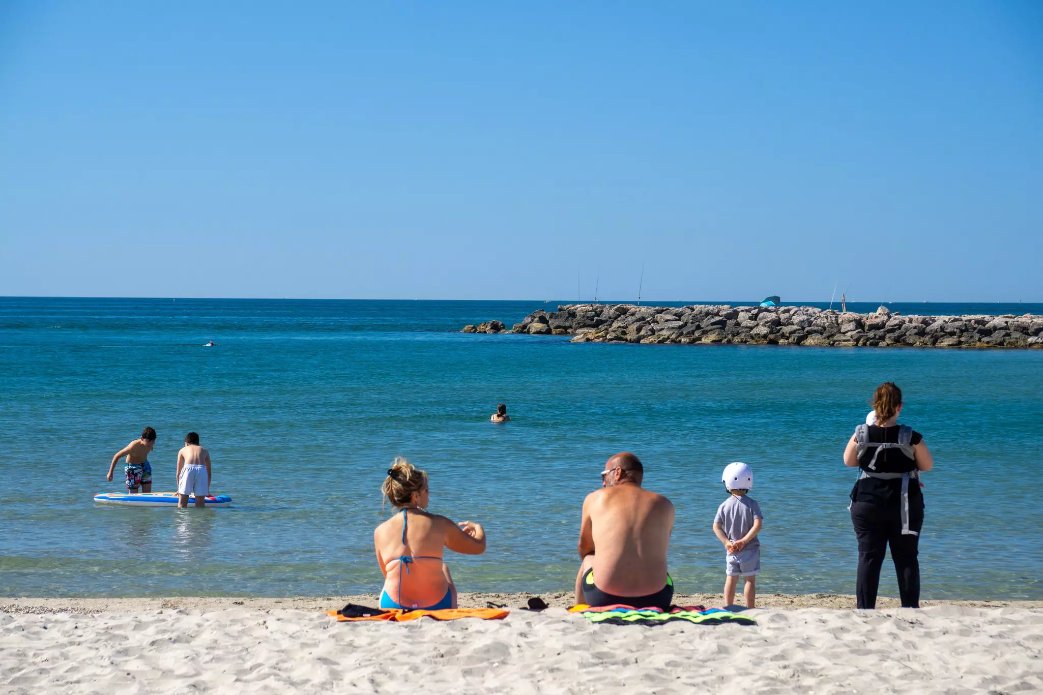 People are seen from behind sitting on a beach