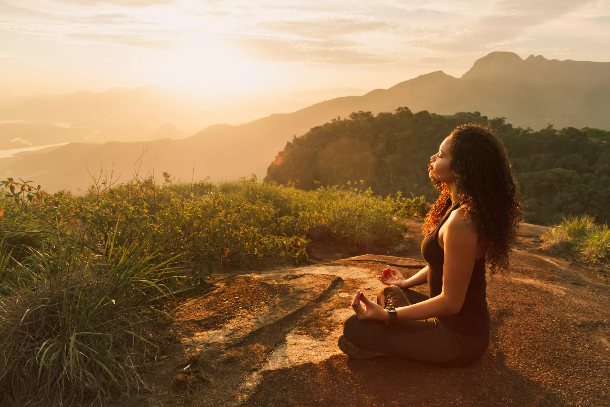 Young woman meditating on a mountain top in Rio de Janeiro.