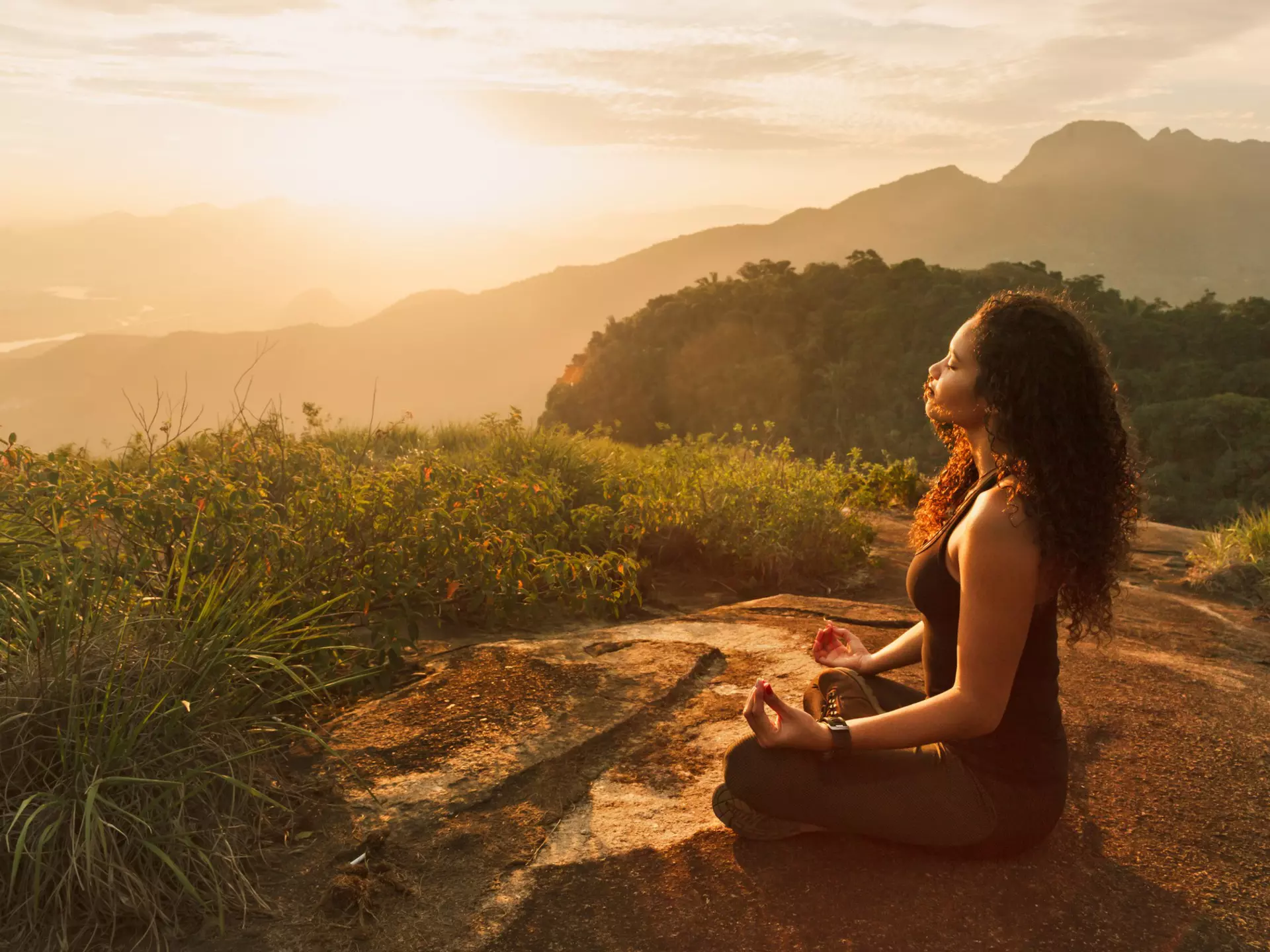 Young woman meditating on a mountain top in Rio de Janeiro.