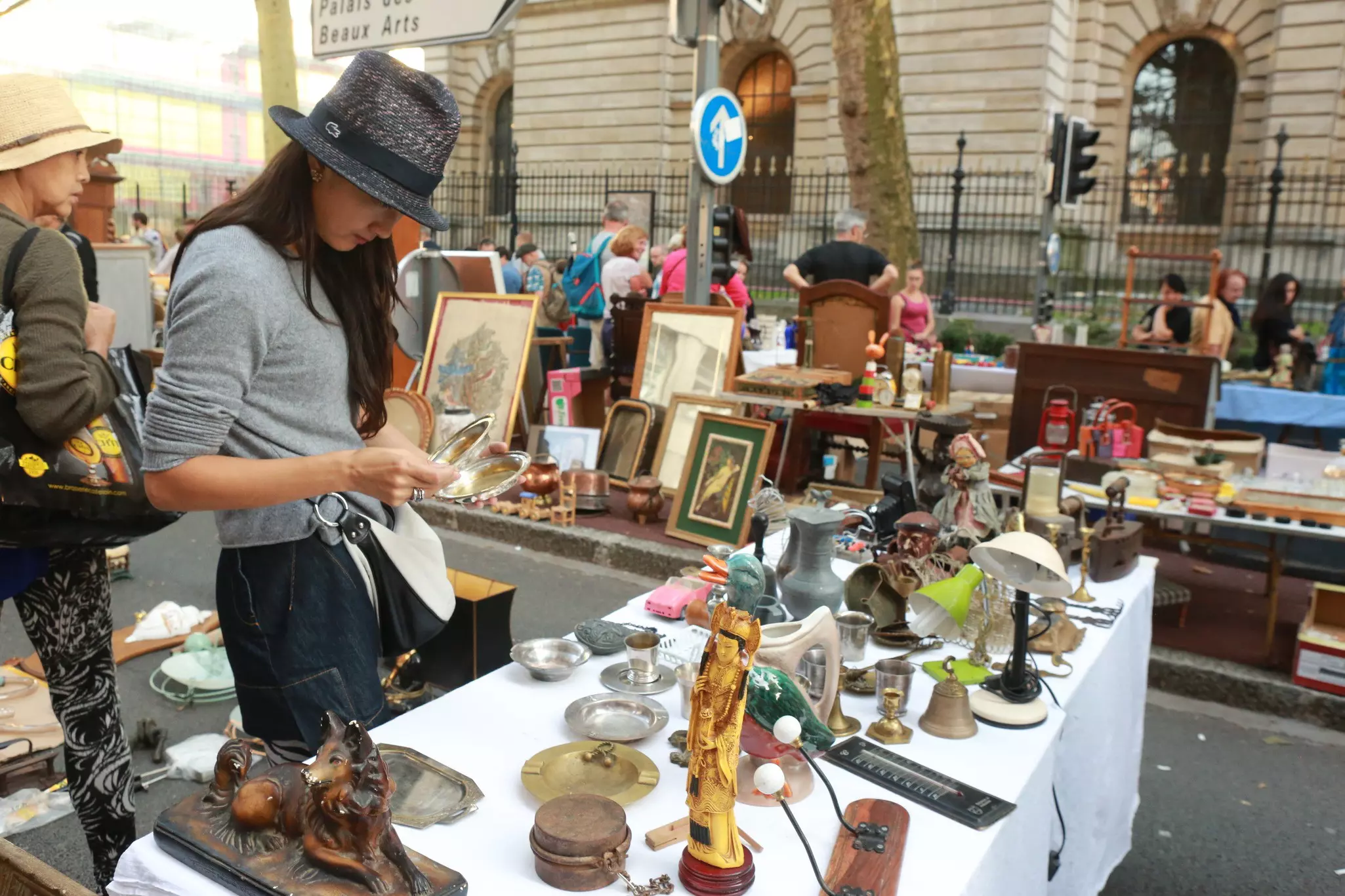 A woman sorts through a collection of items at a flea market stall
