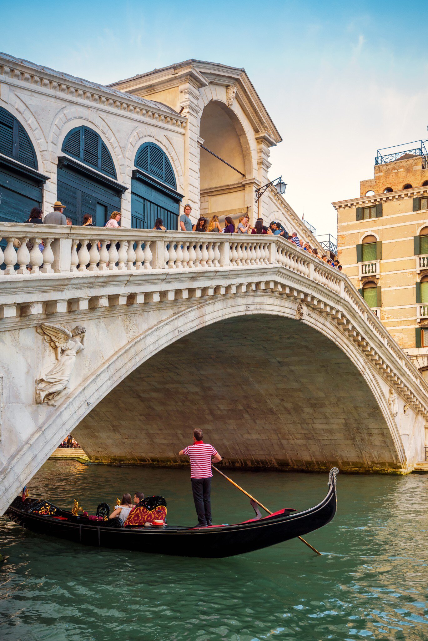 A gondola passing on the Grand Canal under the Ponte di Rialto (Rialto Bridge) in Venice, Italy.