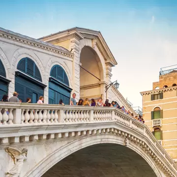 A gondola passing on the Grand Canal under the Ponte di Rialto (Rialto Bridge) in Venice, Italy.