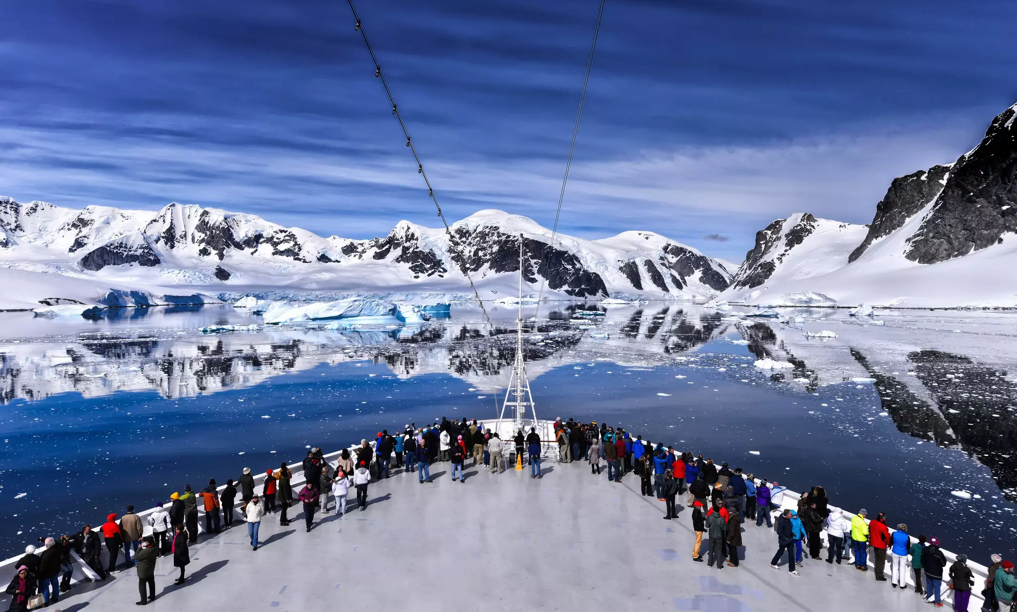 Passenger on the bow of a large passenger cruise ship along the coast of Antarctica