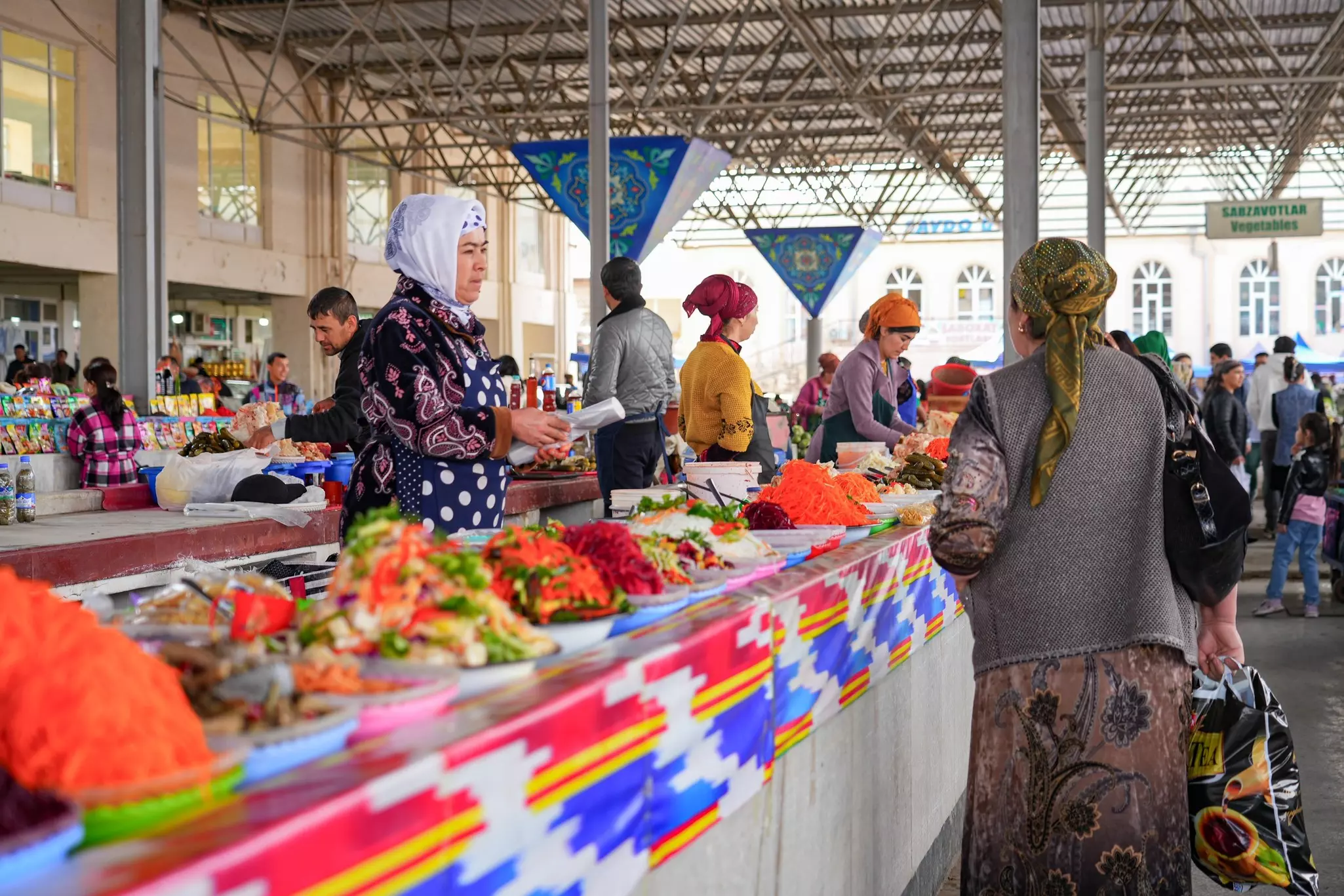 Women man a stall selling salads and prepared food in a covered market.