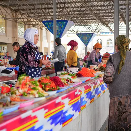 Female vendors in headscarves sell salads and other foods in a covered market hall.