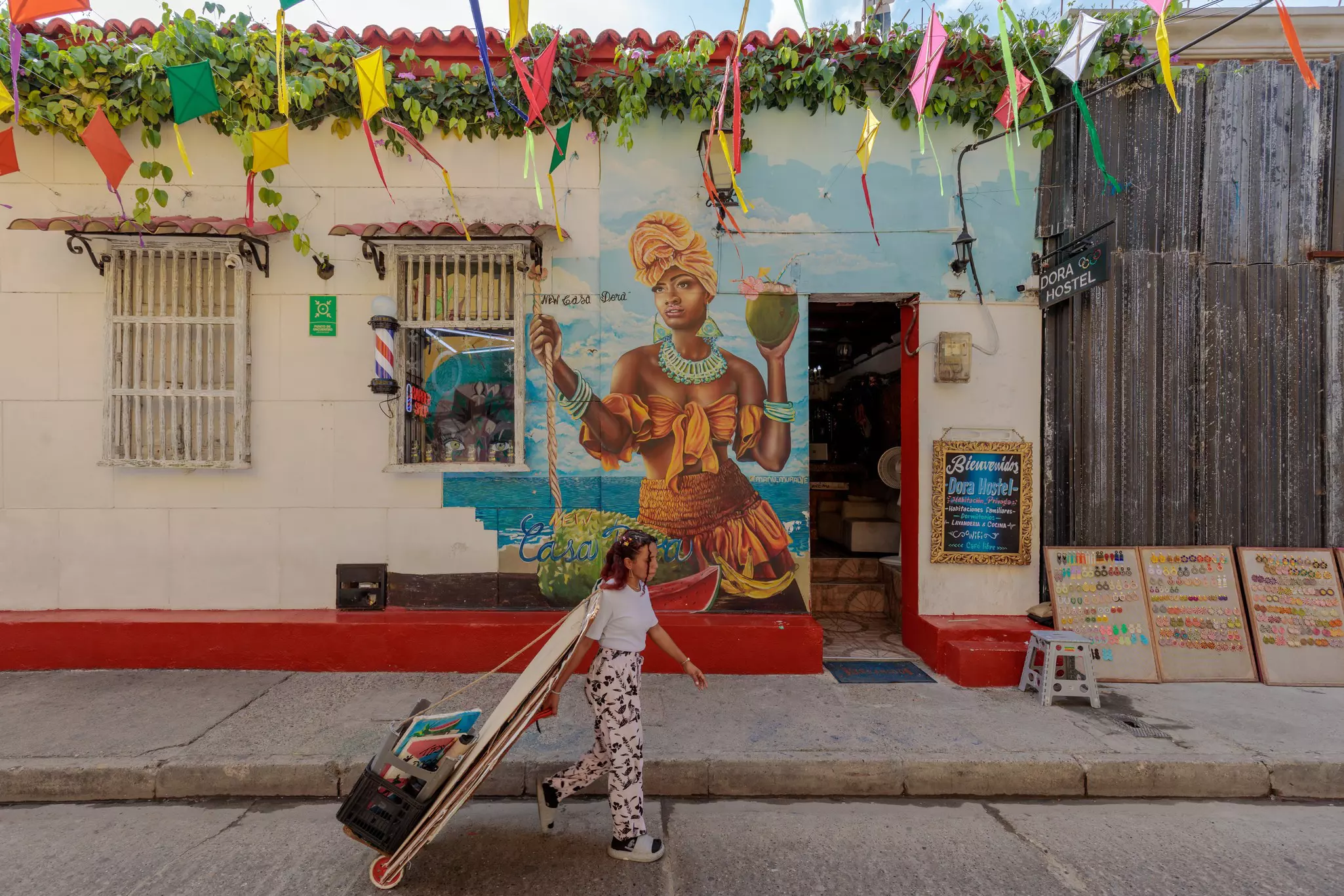 A woman holding artwork walks past a mural