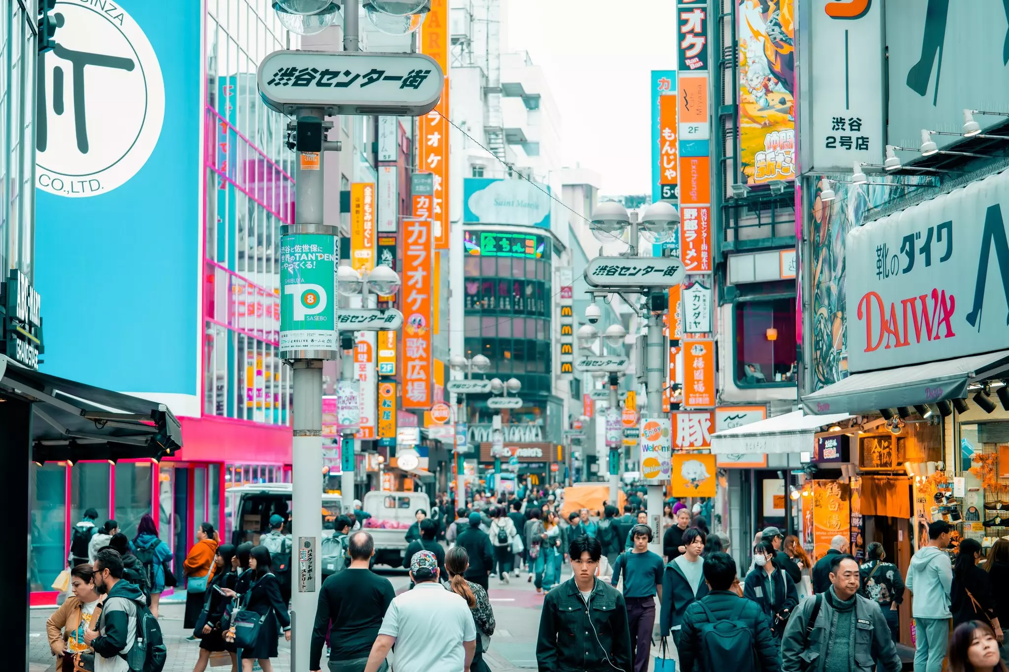 A busy street in Shibuya district in Tokyo, Japan, with shop signs and pedestrians.