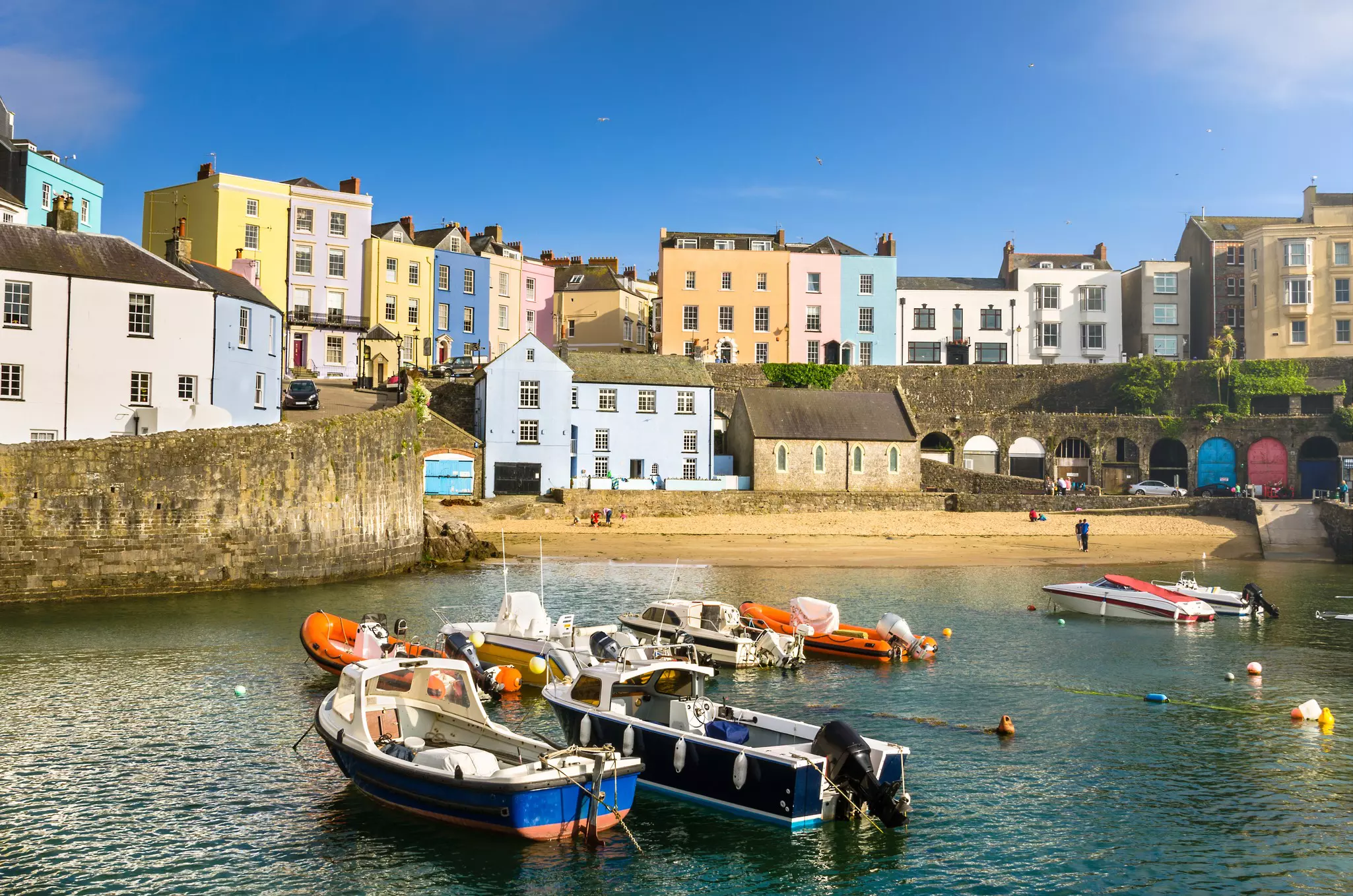 Pastel colored buildings alongside the harbor in the town of Tenby, Wales.