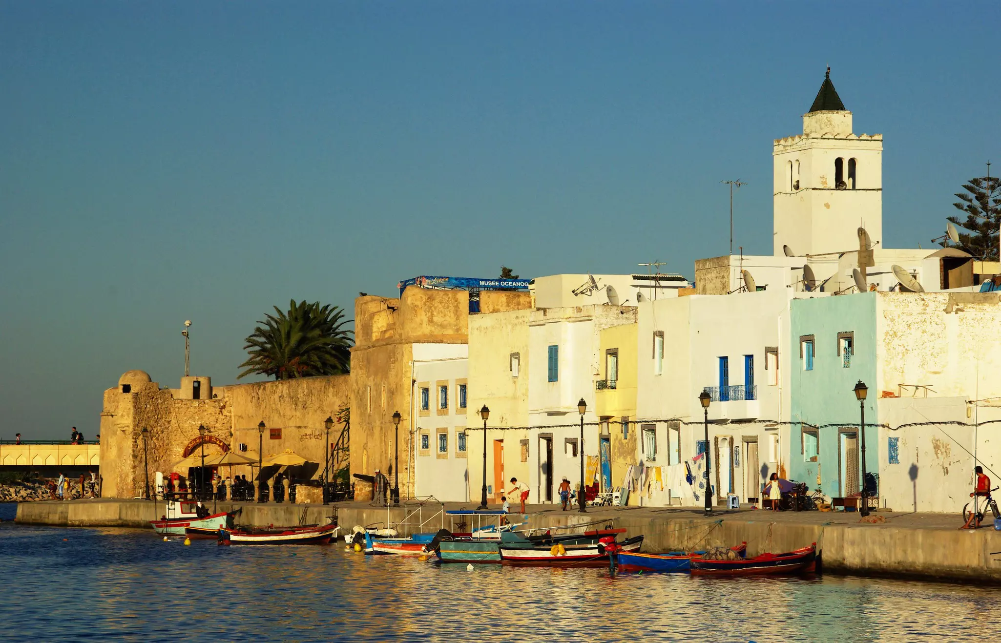 A quiet harbor lined with brightly-colored low buildings at sunset