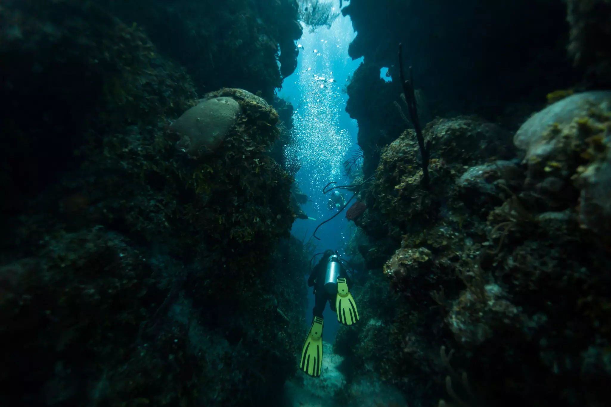 Scuba diver swims through tunnel in Blue Hole, Caribbean Sea, Belize.