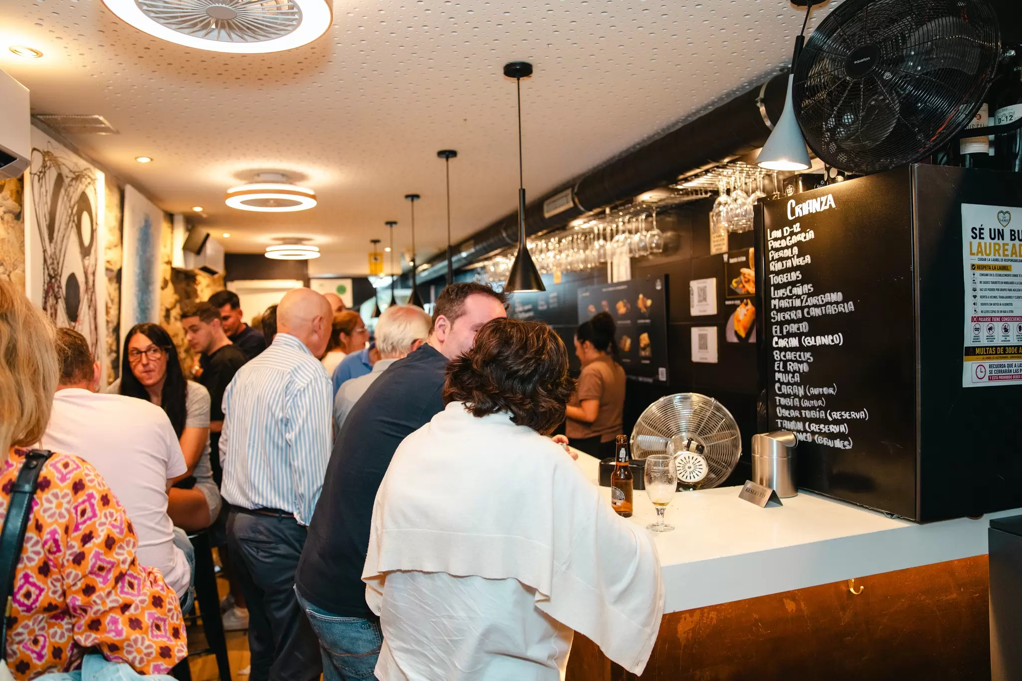 People sitting at a bar in a full, brightly lit restaurant
