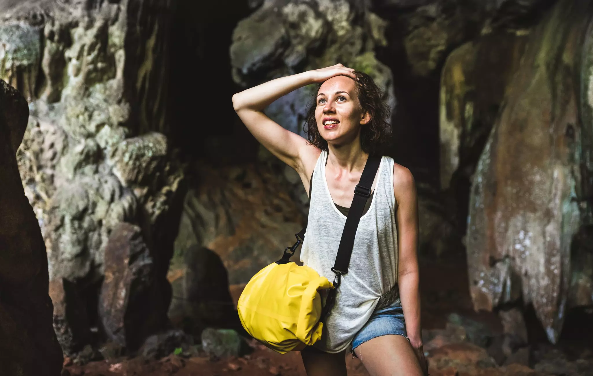 Young woman traveler at cave entrance on island hopping in Cheow Lan Lake.