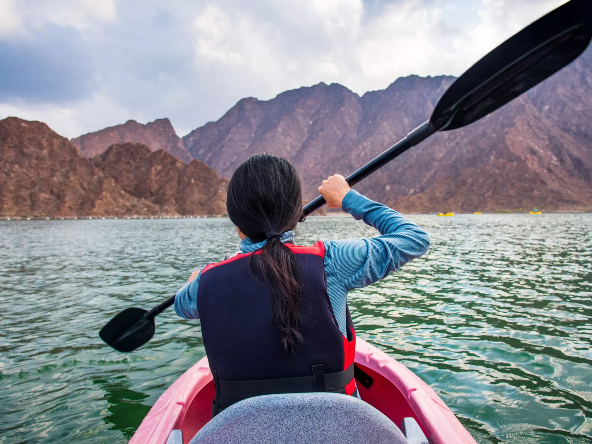 A rear shot of a woman kayaking in a lake