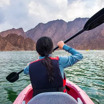 A rear shot of a woman kayaking in a lake
