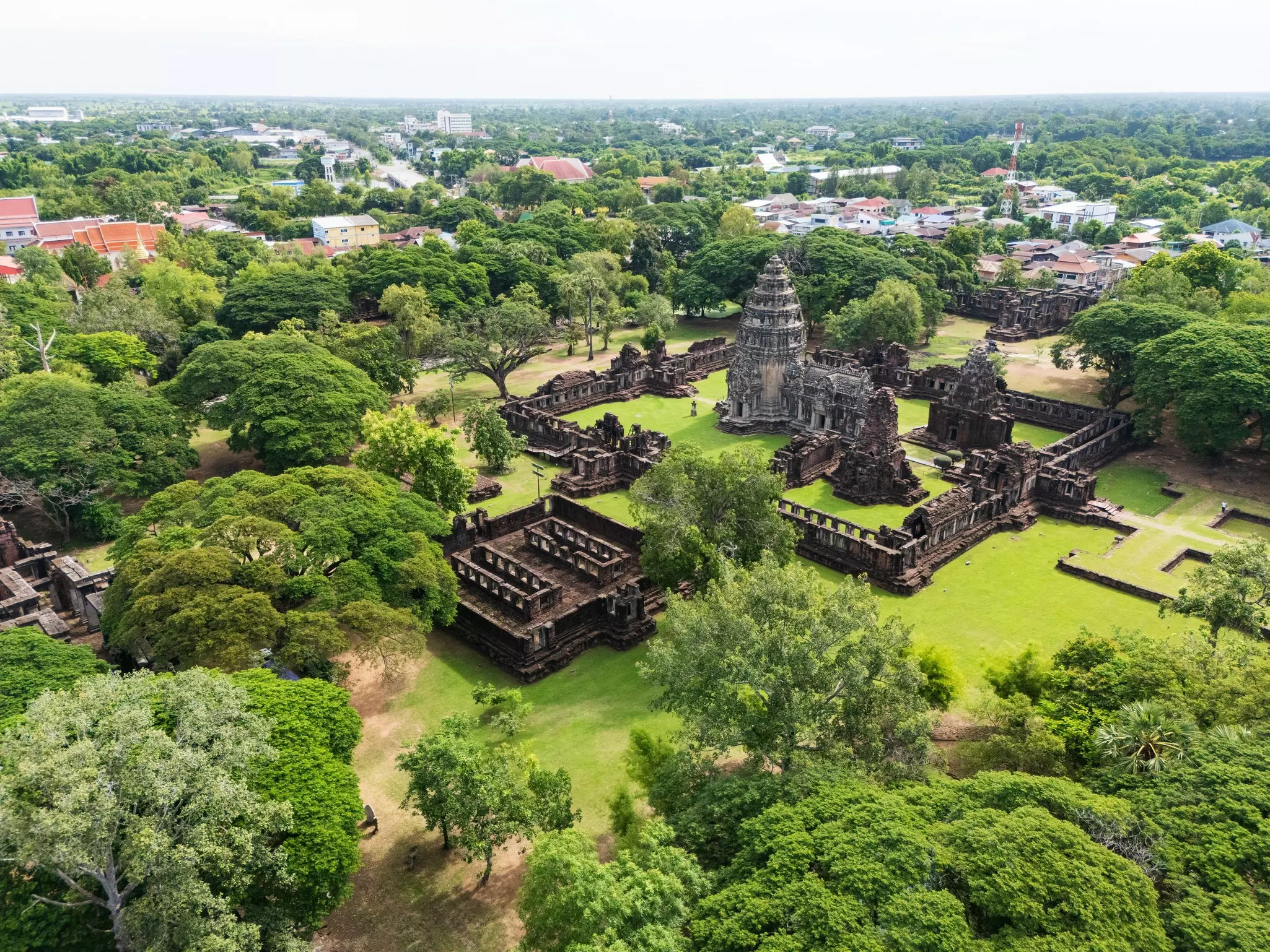 A massive ancient temple surrounded by fields and trees.