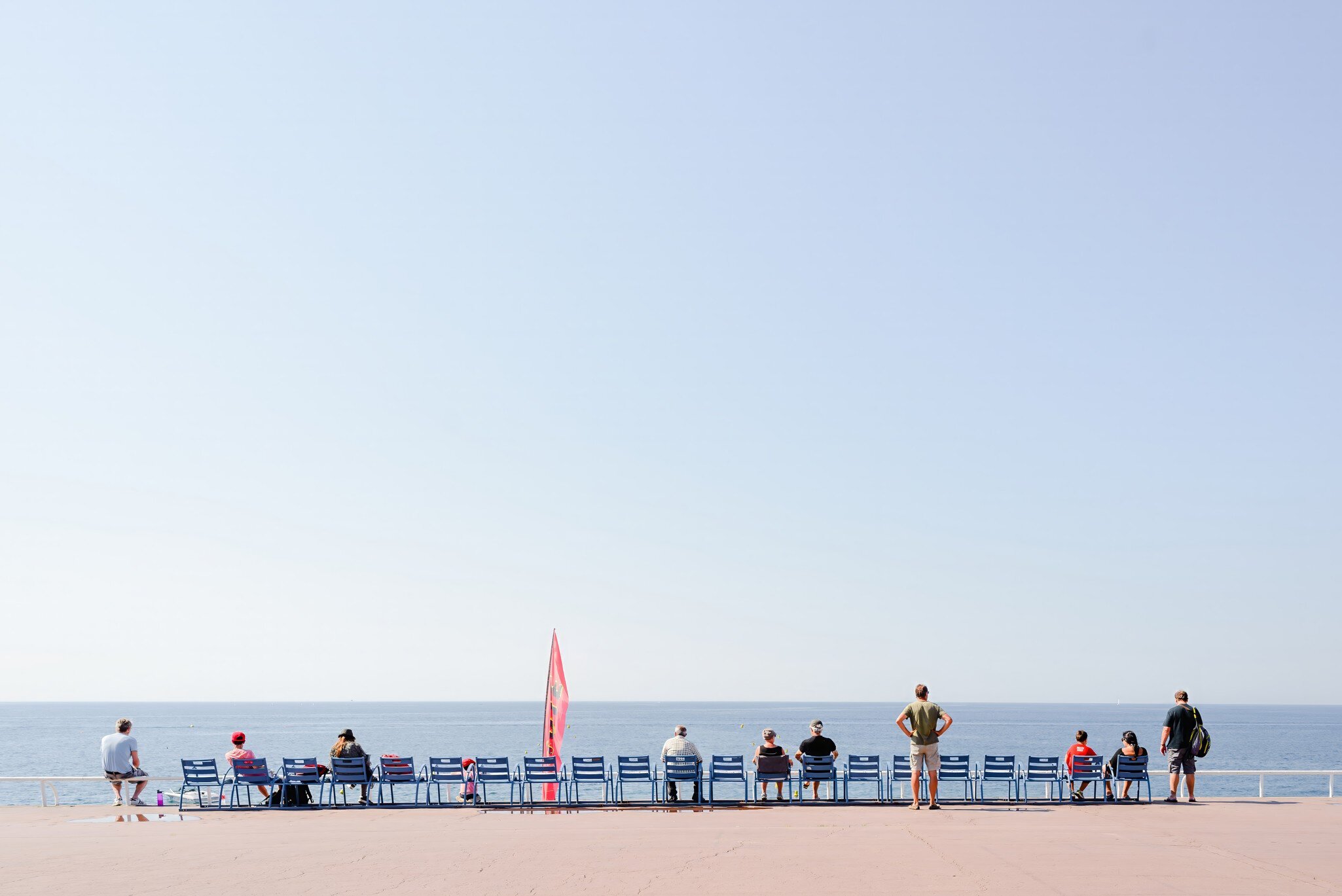 People relaxing on the Promenade des Anglais in Nice, France, horizon in the back.