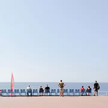 People relaxing on the Promenade des Anglais in Nice, France, horizon in the back.