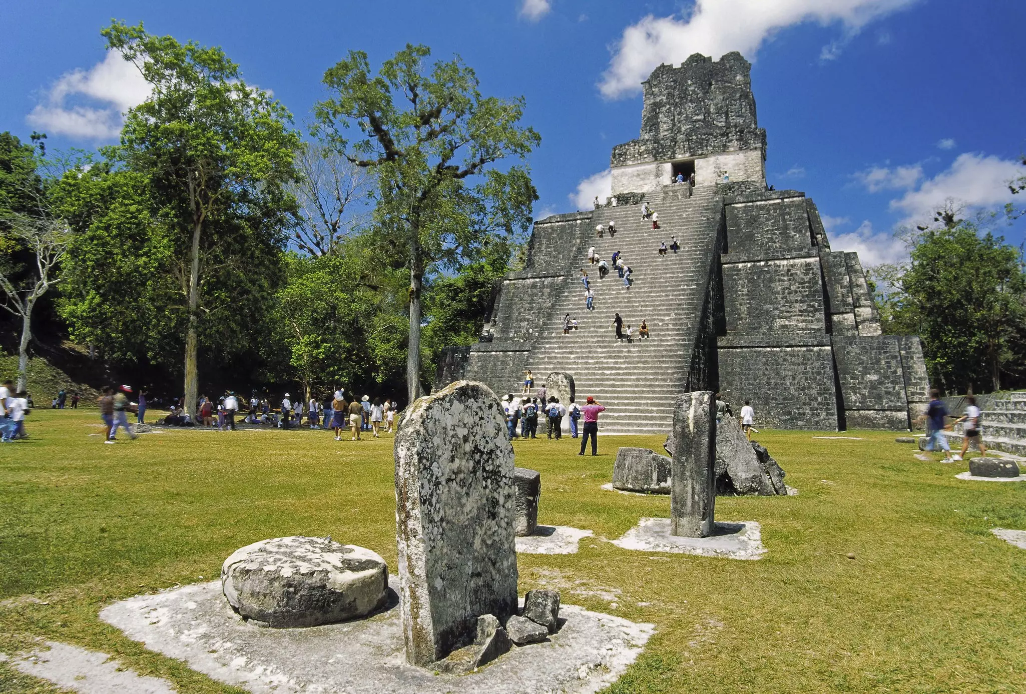 Ancient pyramids in Tikal with tourists climbing the steep steps to reach the top