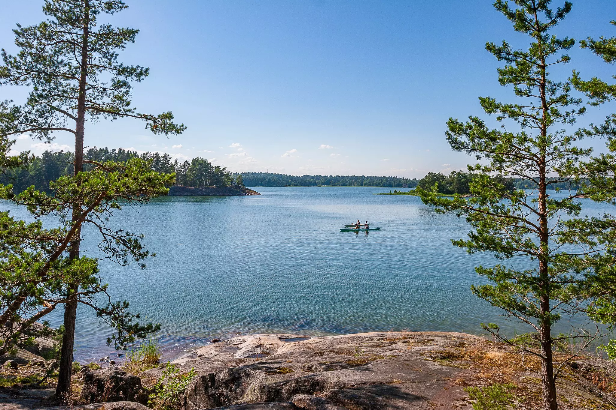 Kayakers offshore in the distance, framed by small trees