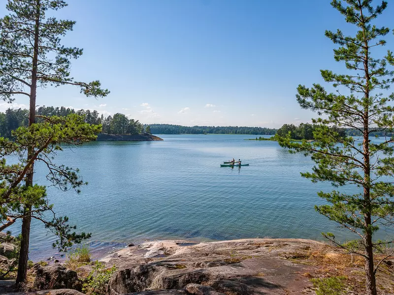 Kayakers offshore in the distance, framed by small trees