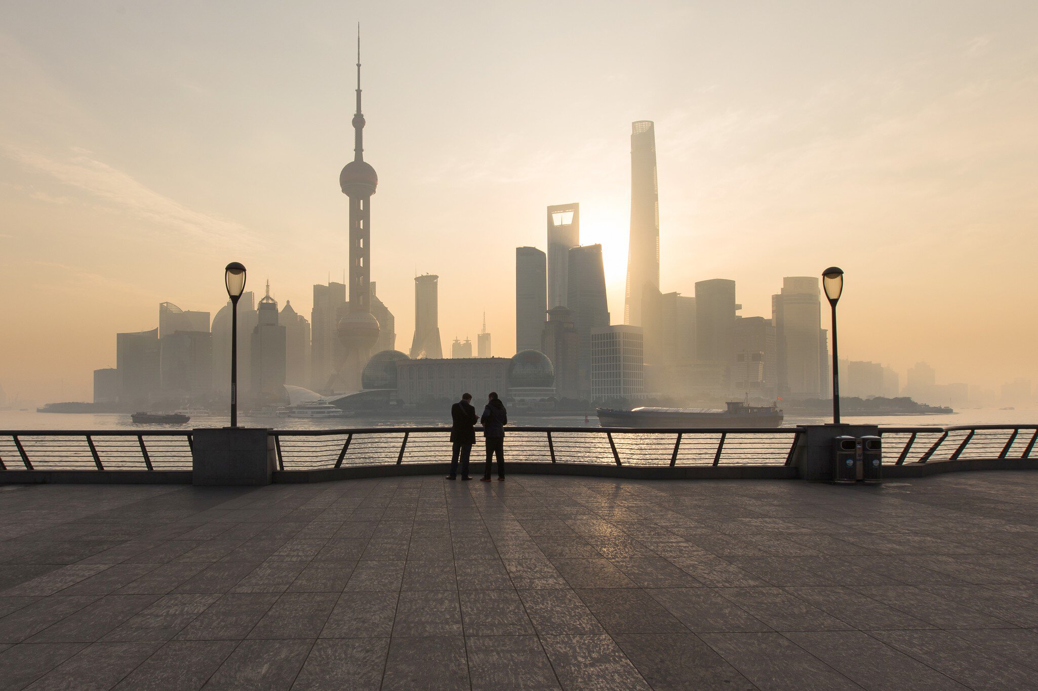 Tourists standing in the Bund, the most scenic spot in Shanghai, China, with skyscrapers in the background.