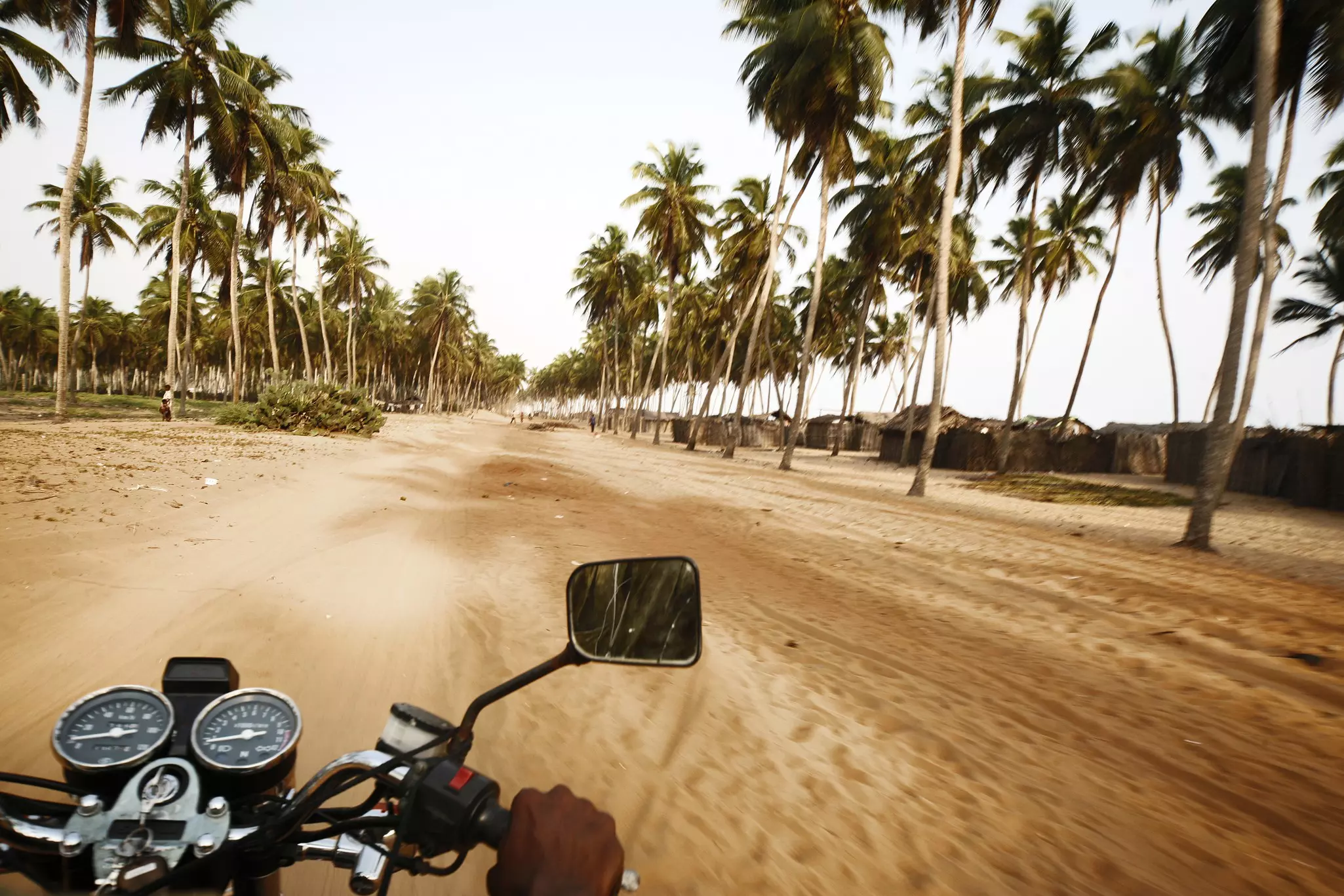 A man riding a motorbike on a beach road in Benin © peeterv / Getty Images