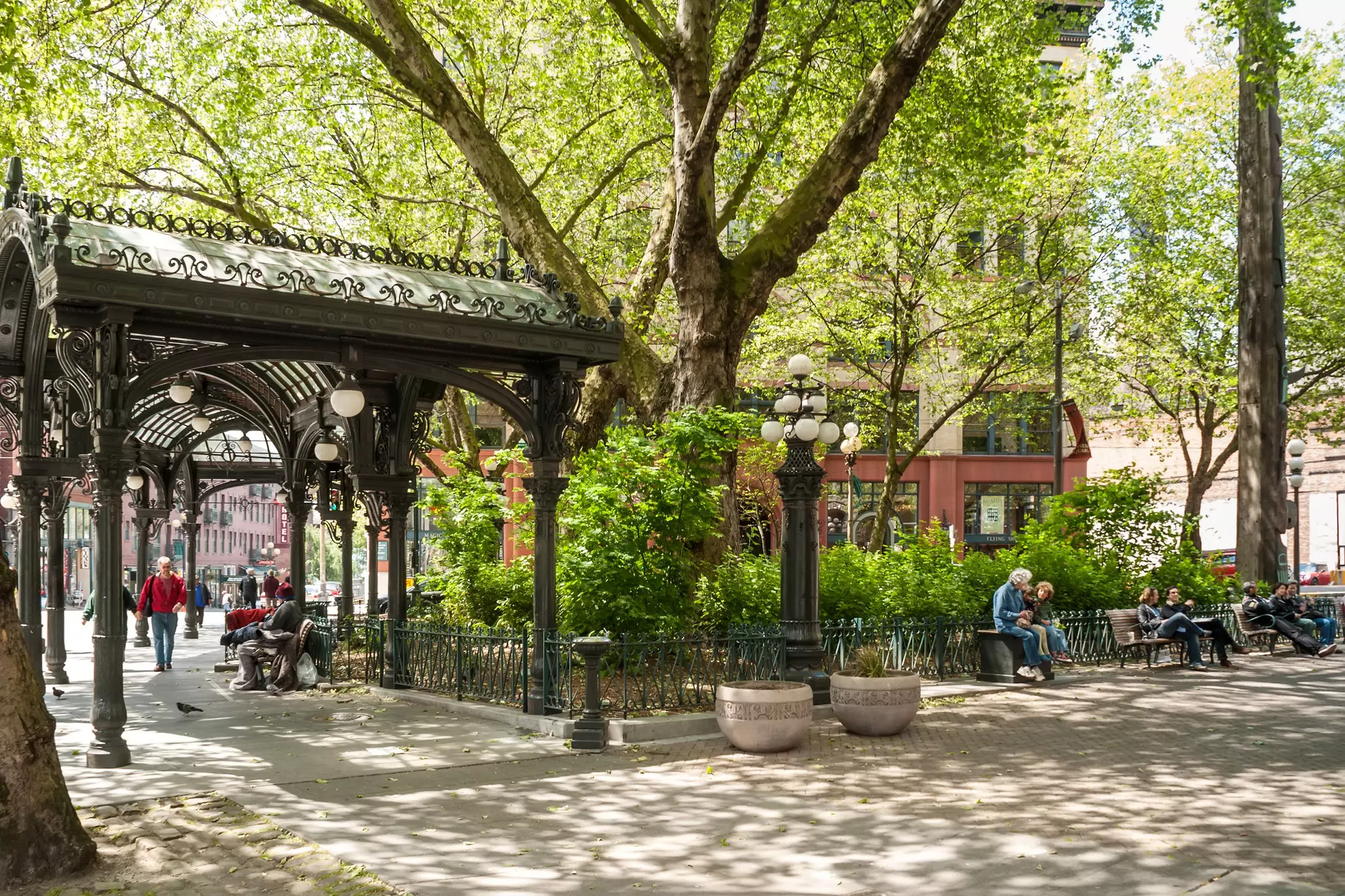 An iron pergola in a park with people sitting on benches in Seattle, Washington.