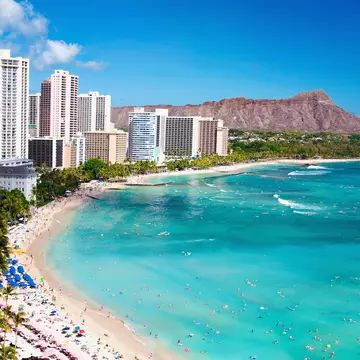 High-rise buildings hug a beach where waves crash against the shore