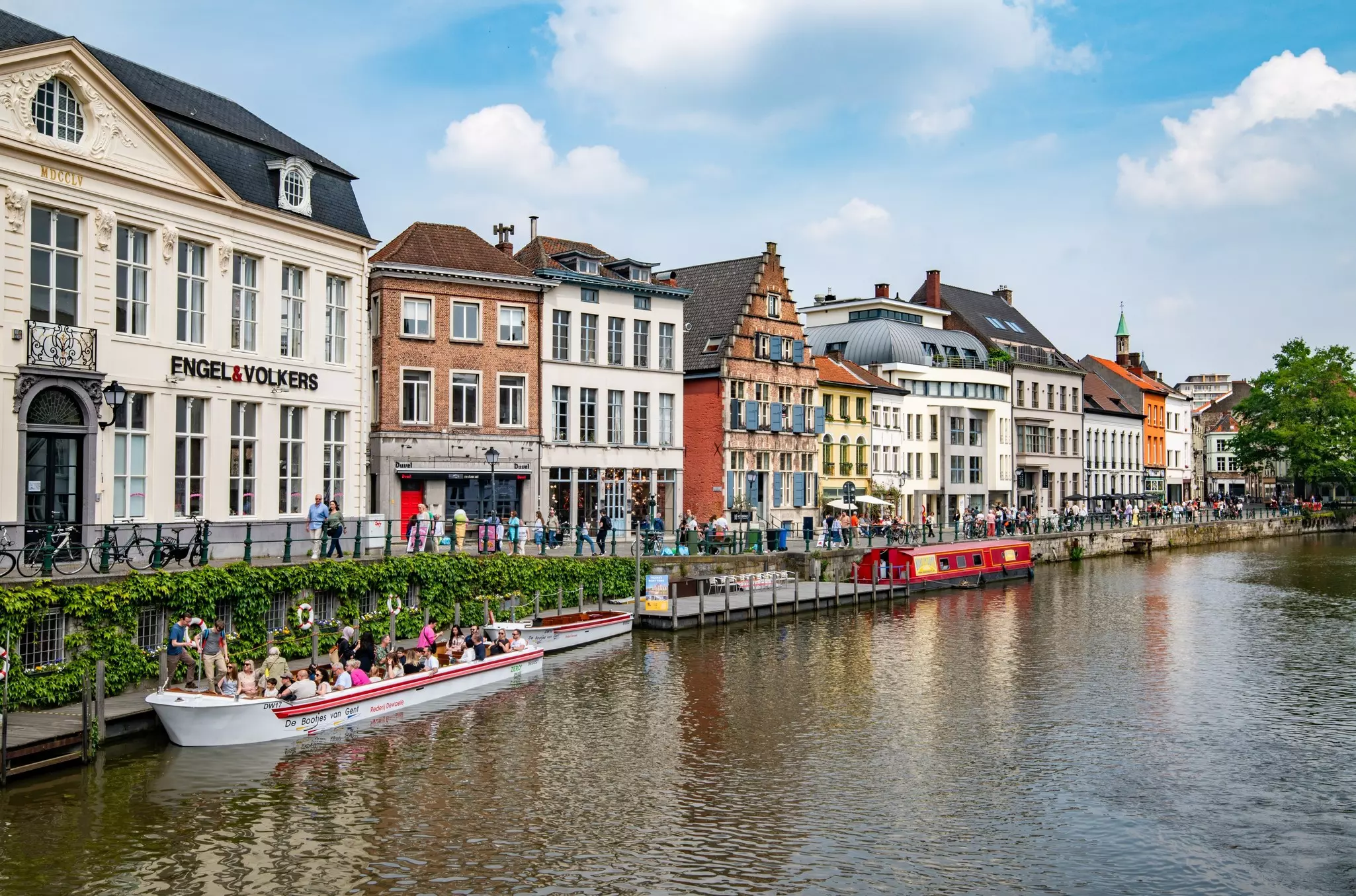 Ghent, Belgium – May 10, 2024: Pretty townhouses perched on the bank of the River Leie in the historic centre. Historic buildings by the side of a picturesque quay.