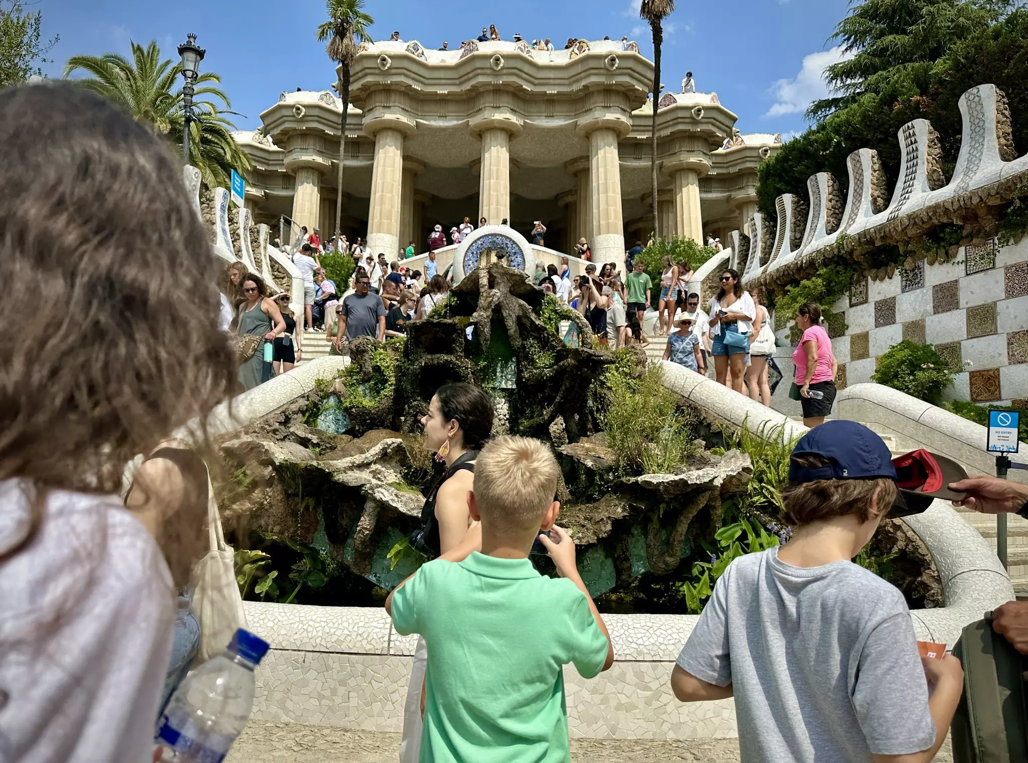 A boy stands on some steps and snaps a photo of a fountain at Parc Güell in Barcelona. IMG1378.jpg