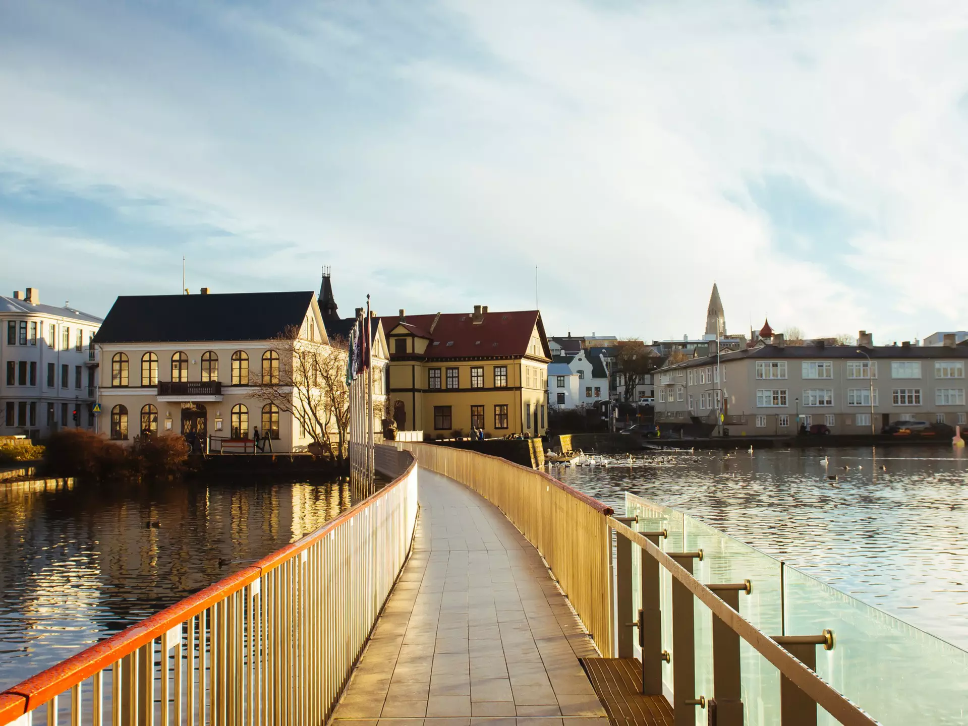 A wide view of a road leading past white apartment buildings in a green hillside.